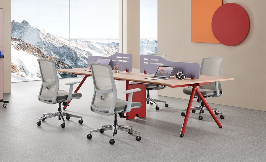 Стол на четверых с откидными створками и четыре офисных стула с серой сеткой в ​​офисе.