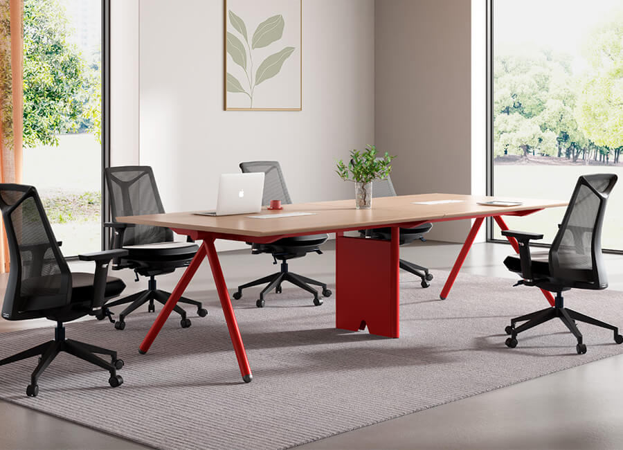 Небольшой стол для переговоров с красным углом и 4 черных офисных сетчатых стула на колесах.
